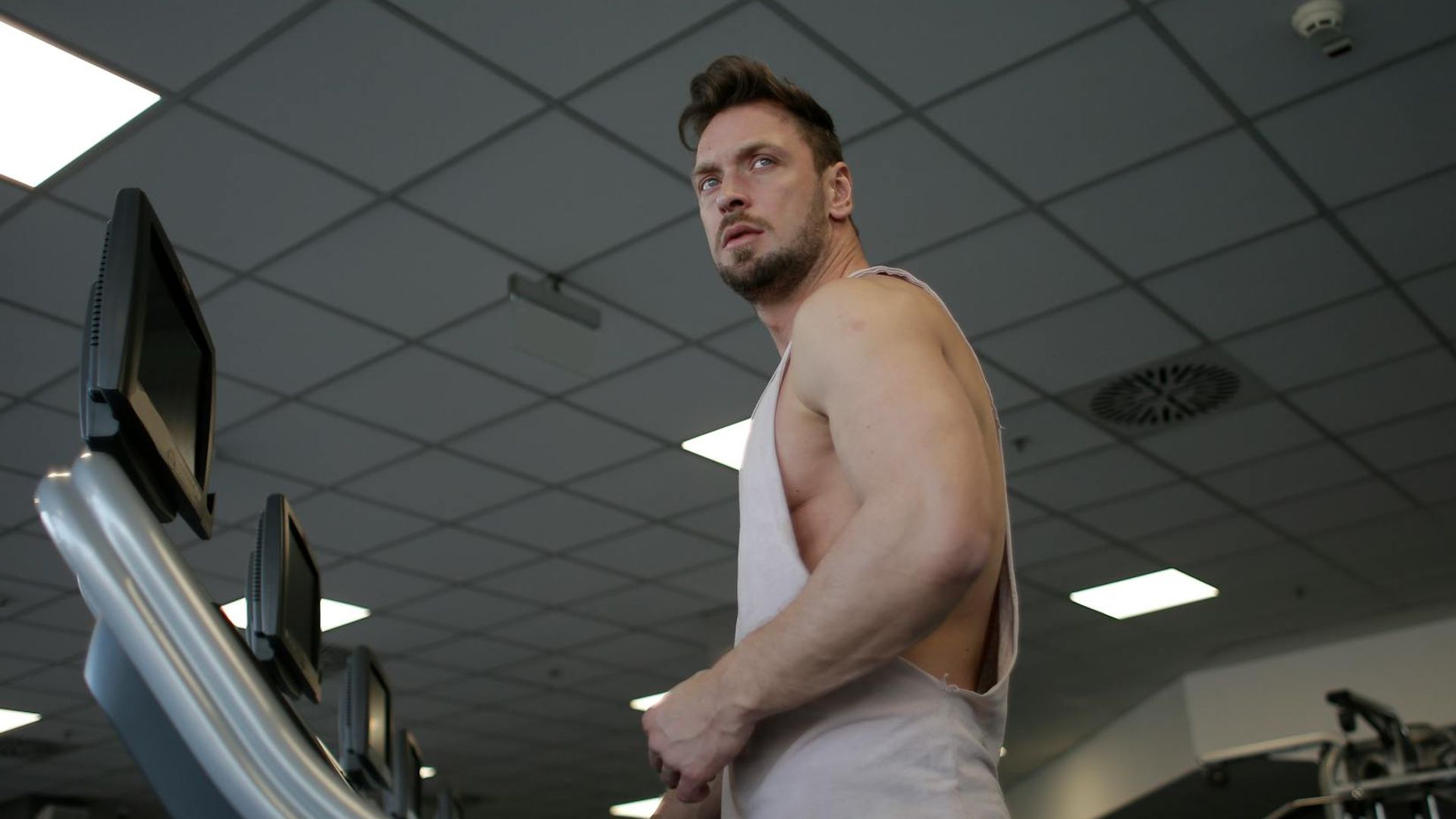 Strong man performing atmospheric exercise in dark gym